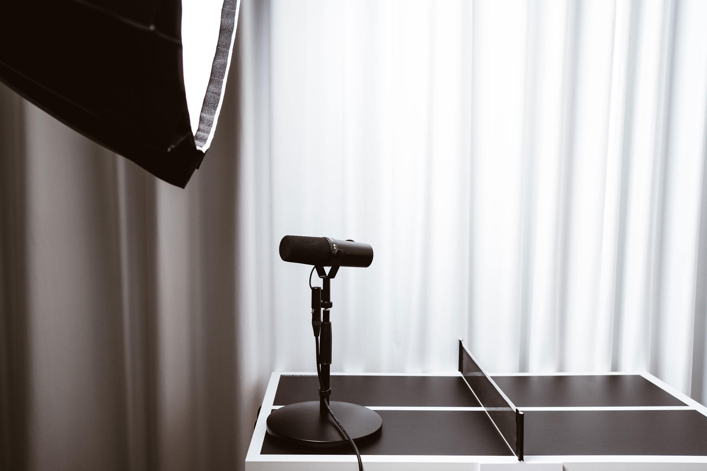 Mikrofon und Softbox vor hellem Vorhang auf Tischtennisplatte